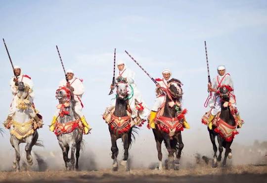 Horsemen performing the Tbourida — the traditional Amazigh fantasia, a display of equestrian skill and collective choreography that has been performed at Moroccan festivals and celebrations for centuries